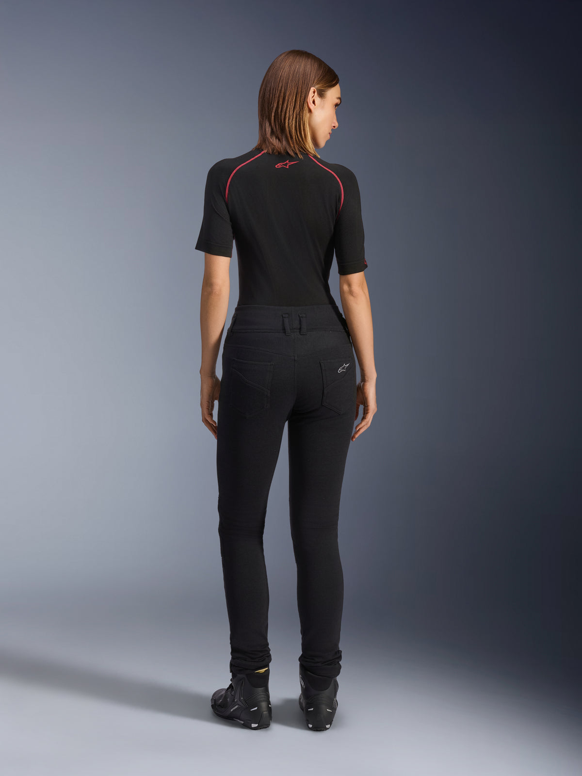 Alpinestars Banshee Leggings för dam, svarta motorcykel-leggings, vy bakifrån som visar en figurnära passform och anatomiskt stretchtyg, med bakfickor och logotypdetalj, bärs med ett svart underställ och körskor, urban motorcykelutrustning för dam