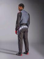 Bakifrån på en modell i Alpinestars KMX-9 V3 Graphic 6 Suit, kartingoverall, Anthracite Black Red, med framträdande vit Alpinestars-logotyp på nedre delen av ryggen, svart och grå paneldesign med röda accenter, buren med matchande racinghandskar och skor.