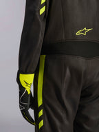 Alpinestars GP Race V3 Suit FIA, svart och fluorescerande gul, närbild på detaljer vid midjan och benets sida, med stretchpaneler i aramid och en matchande racinghandske, professionell bilracingutrustning