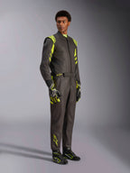 Alpinestars GP Race V3 Suit FIA, racingoverall för bilsport, svart och neongul, bärs av en modell med matchande racinghandskar och racingstövlar, iögonfallande neongula detaljer på axlar och ben, professionell motorsportutrustning