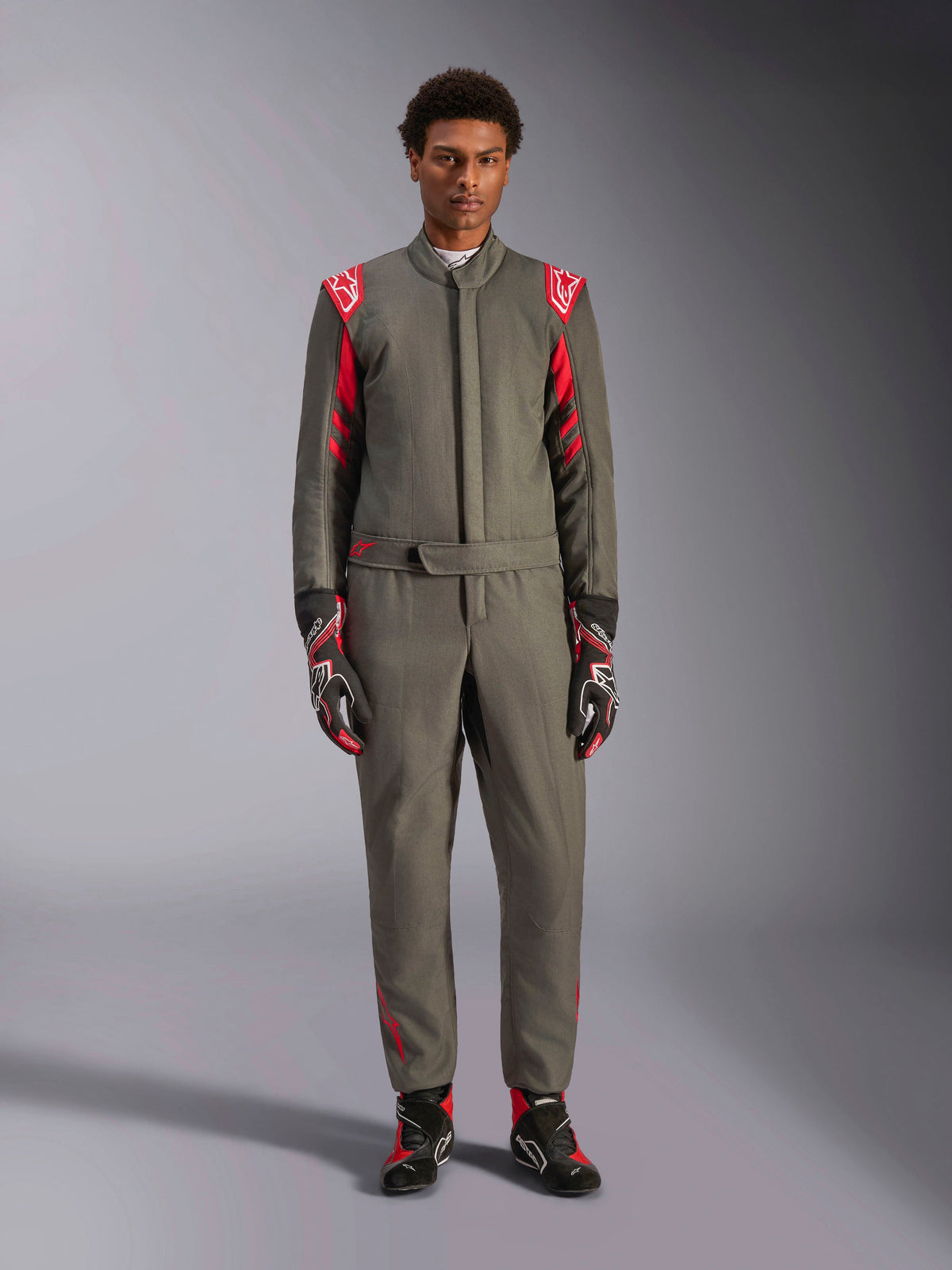 Alpinestars GP Race V3 Suit FIA, racingoverall för bilsport, antracitgrå och röd, bärs av en manlig modell med matchande handskar och stövlar, med röda axelklaffar och logotyper, professionell motorsportutrustning för prestandakörning