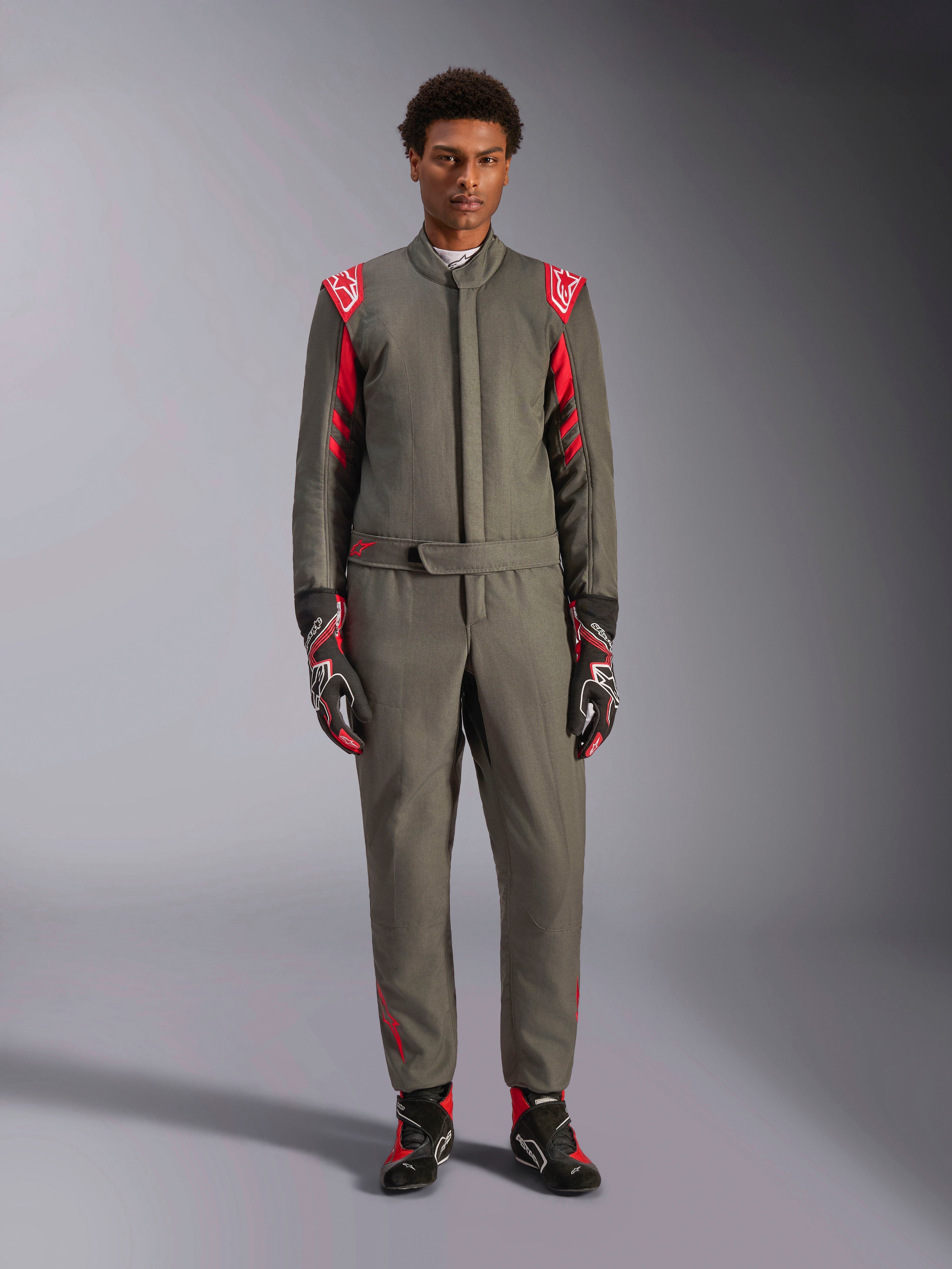 Alpinestars GP Race V3 Suit FIA, racingoverall för bilsport, antracitgrå och röd, bärs av en manlig modell med matchande handskar och stövlar, med röda axelklaffar och logotyper, professionell motorsportutrustning för prestandakörning