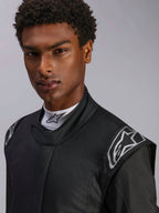 Alpinestars Hypertech V3 Suit, Black Dark Shadow racingoverall, närbild på manlig modell, silverfärgade axellogotyper, hög krage med vit Alpinestars mock-neck-tröja, professionell skyddsutrustning för motorsport