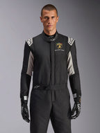 Alpinestars Limited Edition Lamborghini GP Tech V4 Suit, professionell racingdräkt i svart med silver- och gulddetaljer, med Automobili Lamborghini Squadra Corse-skölden på bröstet, bärs av en modell med matchande svarta racinghandskar.