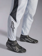 Alpinestars GP Pro Comp V2 FIA racingoverall, grå och svart med stjärnlogotyp på benet och matchande svarta racingstövlar.