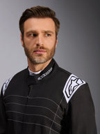 Alpinestars KMX-9 V3 Suit, kartingoverall, svart och vit, närbild på en modell som bär dräkten, visar den vita Alpinestars-logotypen på axelepåletten, märkt ergonomisk krage och vita horisontella kontrastsömmar.
