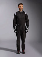Alpinestars KMX-9 V3-ställ, svart och vit kartingoverall, helfigur på en modell, med vita axellogotyper och detaljer, stylad med svarta och vita racinghandskar och svarta skor med röda skosnören, athletic-regular passform för professionell kartingutrustning.