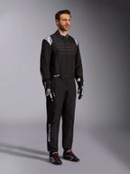 Alpinestars KMX-9 V3 kartingoverall, svart och vit, manlig modell i komplett racingoverall med vit Alpinestars-logotyp på axelklaffarna, kombinerad med svarta och vita racinghandskar och svarta kartingskor med röda skosnören, studiobild som visar fram- och sidoprofil