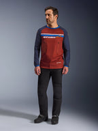 Alpinestars Maxdura Dual Jersey, rostbrun och Mood Indigo, äventyrströja för motorcykel med mesh-torso och marinblå ärmar, bärs av en modell med svarta körbyxor och svarta stövlar, teknisk dual-sport-utrustning för terrängkörning