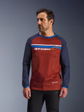 Manlig modell iklädd Alpinestars Maxdura Dual Jersey, rostbrun och marinblå äventyrsmotorcykeltröja, med dubbla bröstfickor med dragkedja, horisontell bröstrand med logotyp, teknisk mesh-torso och hållbara vävda ärmar.