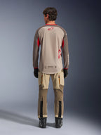 Alpinestars Maxdura Dual Jersey i Aluminum Walnut, sedd bakifrån, beige mesh-torso med bruna ärmar och röda logotyper, förlängt bakstycke, kombinerat med adventure-körbyxor och svarta stövlar.