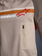 Alpinestars Maxdura Dual Jersey, Aluminum Walnut, närbild på torson i mesh, horisontell orange och vit rand med röd logotyp, vertikal bröstficka med dragkedja, adventure-motorcykelkläder