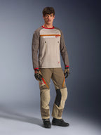 Modell som bär Alpinestars Maxdura Dual Jersey i Aluminum Walnut, med grå mesh-torso, bruna ärmar med röda muddar och bröstfickor med dragkedja, stylad med matchande off-road-utrustning för adventure-körning.