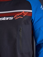 Alpinestars Maxdura Dual Jersey, närbild på bröst och ärm, mörkgrå och kungsblå, med bröstficka med dragkedja, ventilerande mesh-bål och integrerad vaddering på ärmarna, Alpinestars-logotyp över röda och vita ränder