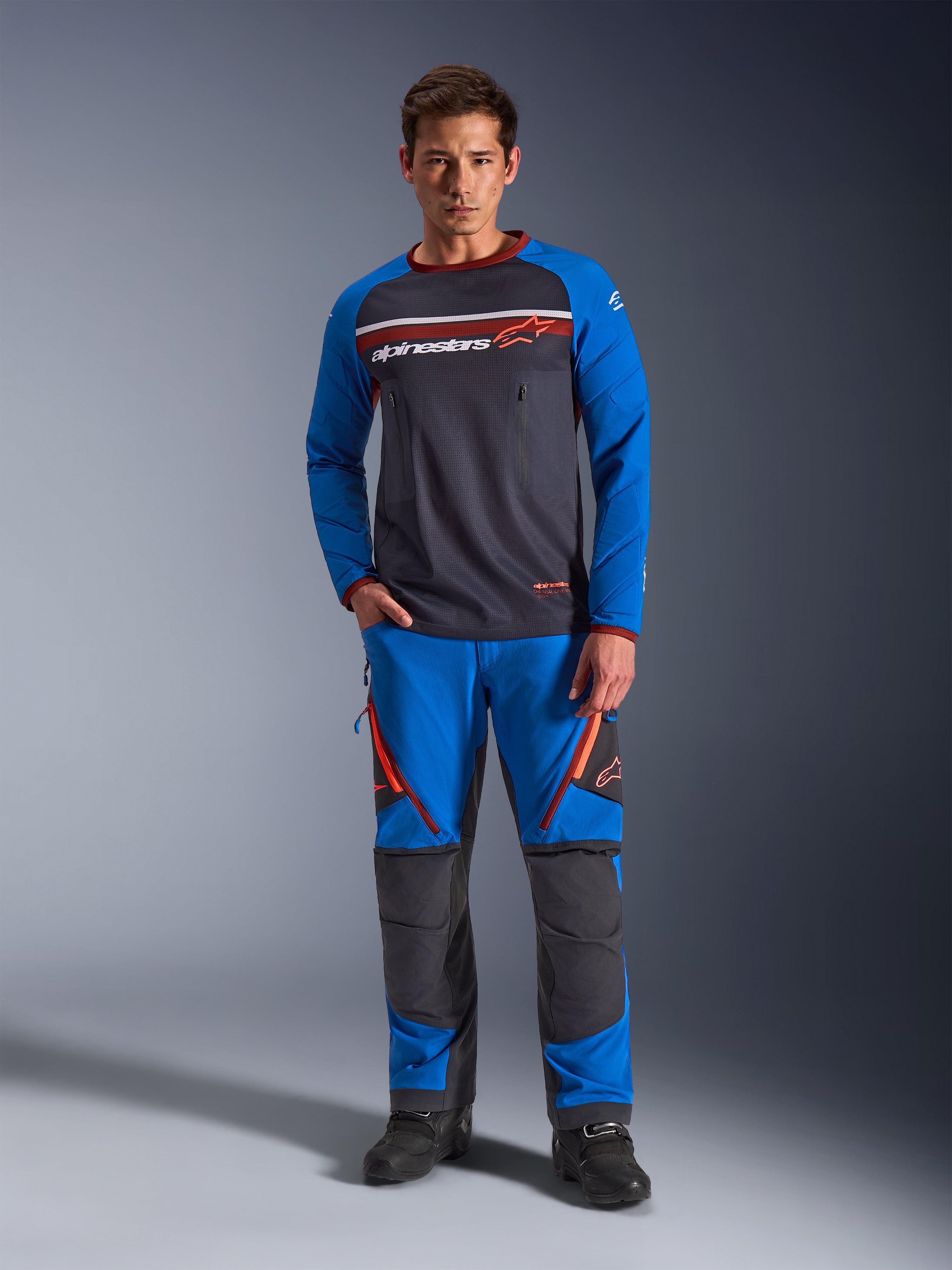 Alpinestars Maxdura Dual Jersey, motorcykeltröja, mörkgrå och kungsblå, torso i helmesh med vadderade ärmar och bröstfickor med dragkedja, vit och orange Alpinestars-logotyp, bärs med matchande äventyrsbyxor och svarta stövlar