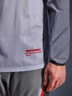 Alpinestars Maxdura Dual Jersey, mellangrå och mörkgrå, närbild som visar ventilerande mesh-bål med röd logotyp, detalj på ficka med dragkedja och integrerad vaddering på ärmen, teknisk motorcykelutrustning för äventyrskörning