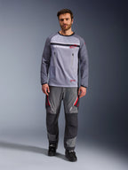Alpinestars Maxdura Dual Jersey, mellangrå och mörkgrå, äventyrsmotorcykeltröja med torso i mesh och bröstfickor med dragkedja, nötningsbeständiga ärmar med integrerad vaddering, bärs med matchande grå funktionsbyxor med röda detaljer, teknisk terrängkörningsutrustning