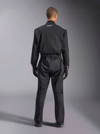 Alpinestars Kart Indoor V2 Suit, Black Karting Suit, rear full-body view on model, featuring white piping details and a small white Astars logo on the back collar, elastic waist belt, worn with black racing gloves, one-piece motorsport apparel.