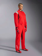 Alpinestars Kart Indoor V2-overall, röd kartingoverall, bärs av en modell med matchande röda och svarta handskar och skor, med vita logotyper på axlar och underben, svarta detaljer, designad för rekreationskarting och inomhusbanor