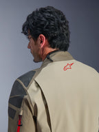 Alpinestars Nazca 3L GORE-TEX PRO-jacka, Walnut Rock Brown äventyrsjacka, närbild på rygg och axel, röd stjärnlogotyp på nacken, grå strukturerade förstärkningspaneler, slitstark textilkonstruktion för motorcykelkörning