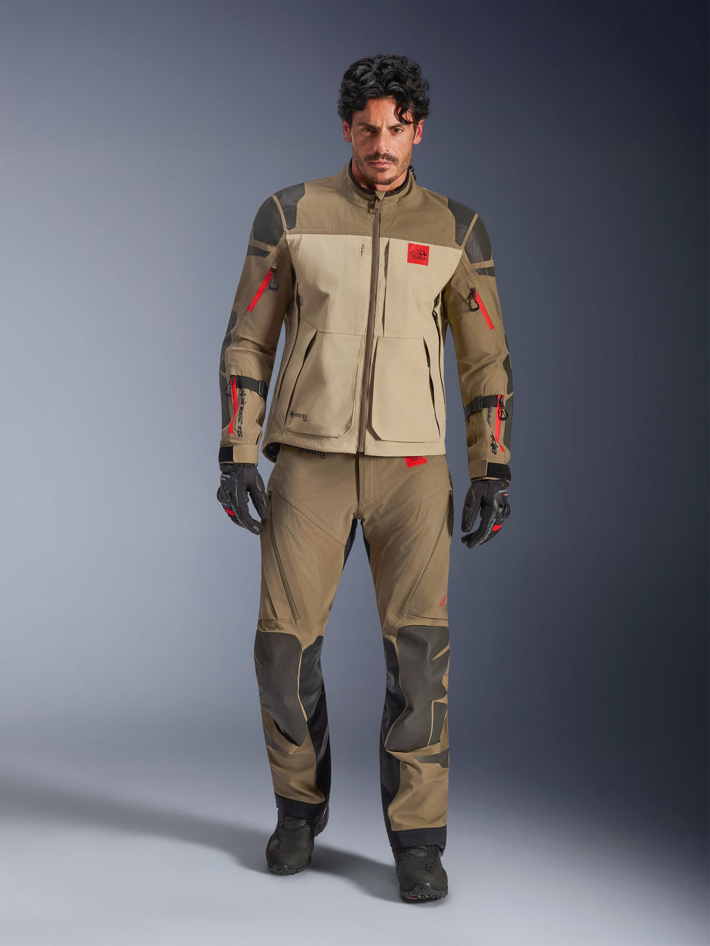 Alpinestars Nazca 3L GORE-TEX PRO-jacka, Walnut Rock Brown, äventyrsjacka för motorcykelkörning som bärs med matchande byxor och handskar, med röda dragkedjedetaljer, 'All Terra'-logotyp på bröstet och robust textilkonstruktion.
