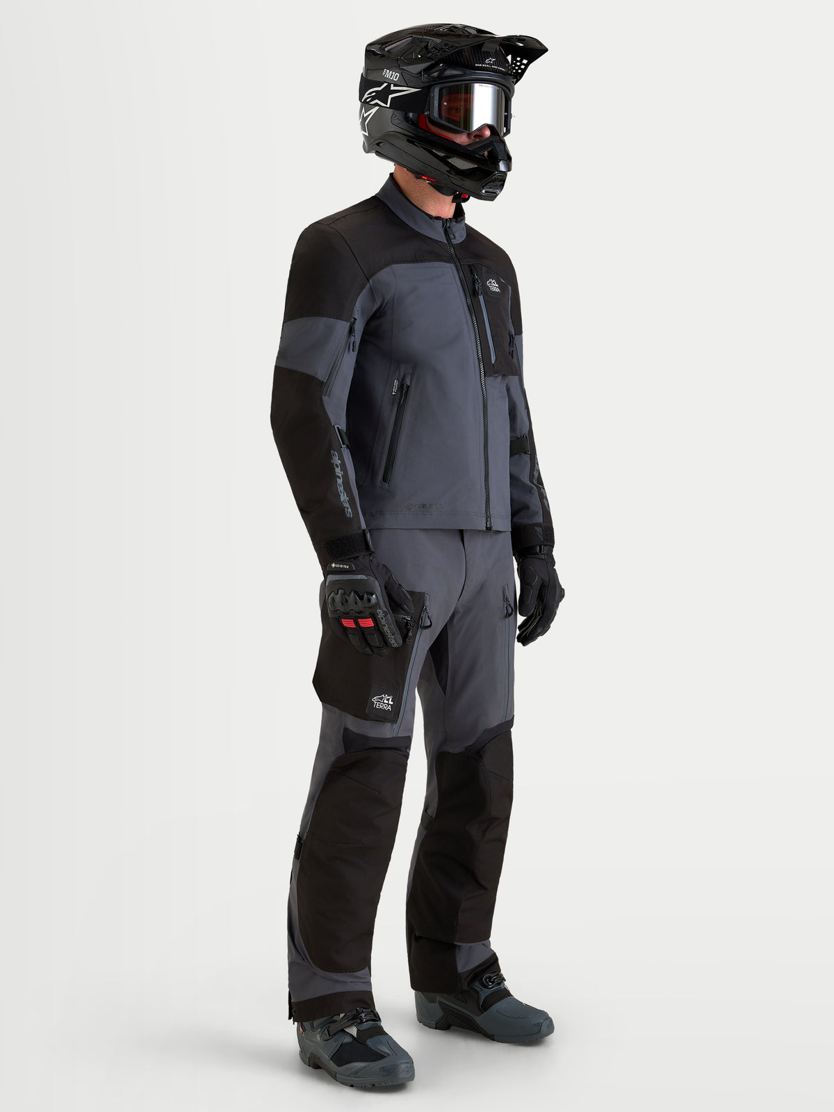 Alpinestars Arenis Gore-Tex gear set, äventyrsmotorcykeljacka och byxor för herr i svart och mörkgrå, sidoprofil på en modell med matchande utrustning och hjälm