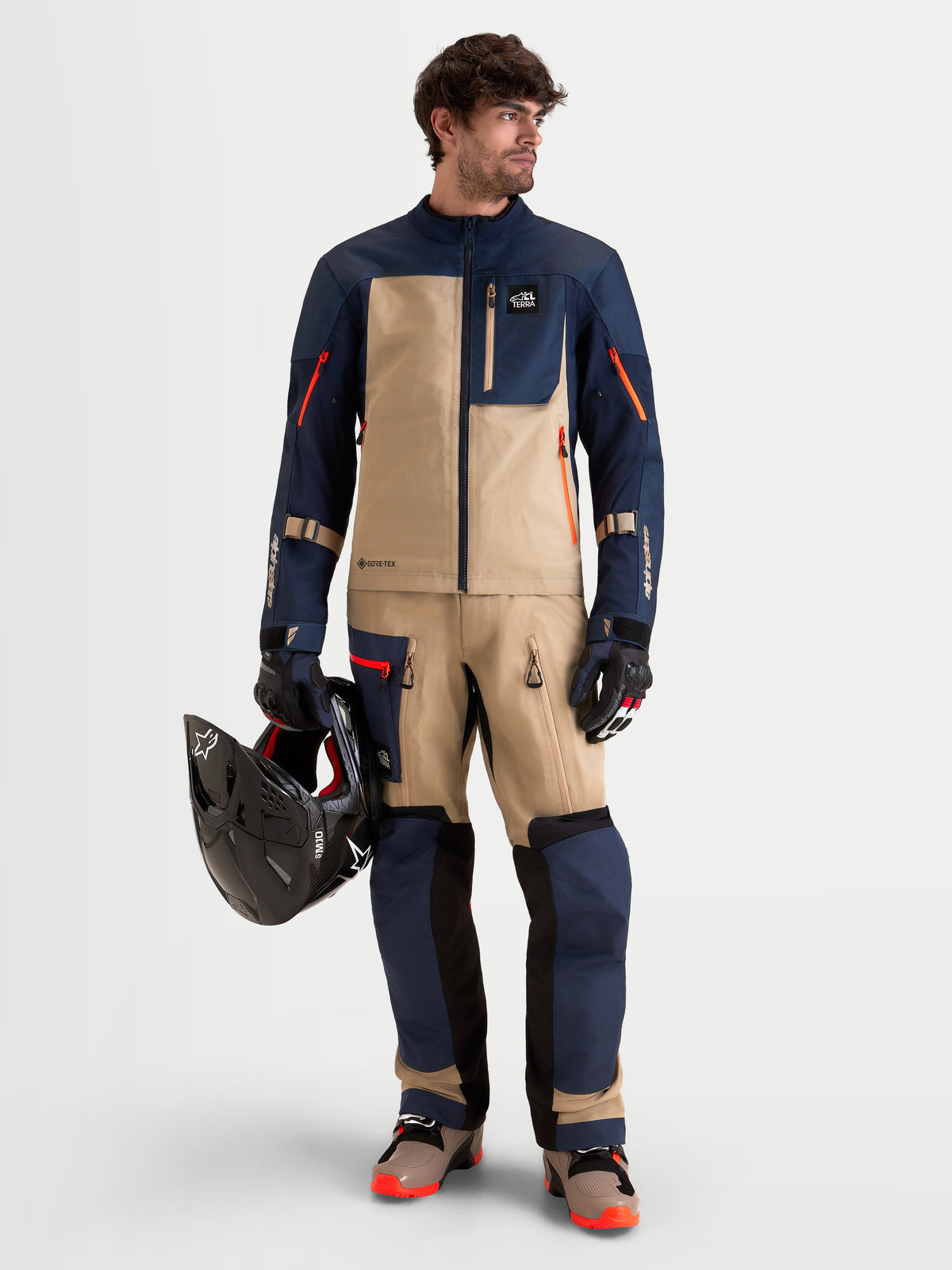 Alpinestars Arenis Gore-Tex jacka, äventyrsmotorcykeljacka för herr i mörkblått och aluminiumbeige, bärs av en modell som håller en hjälm