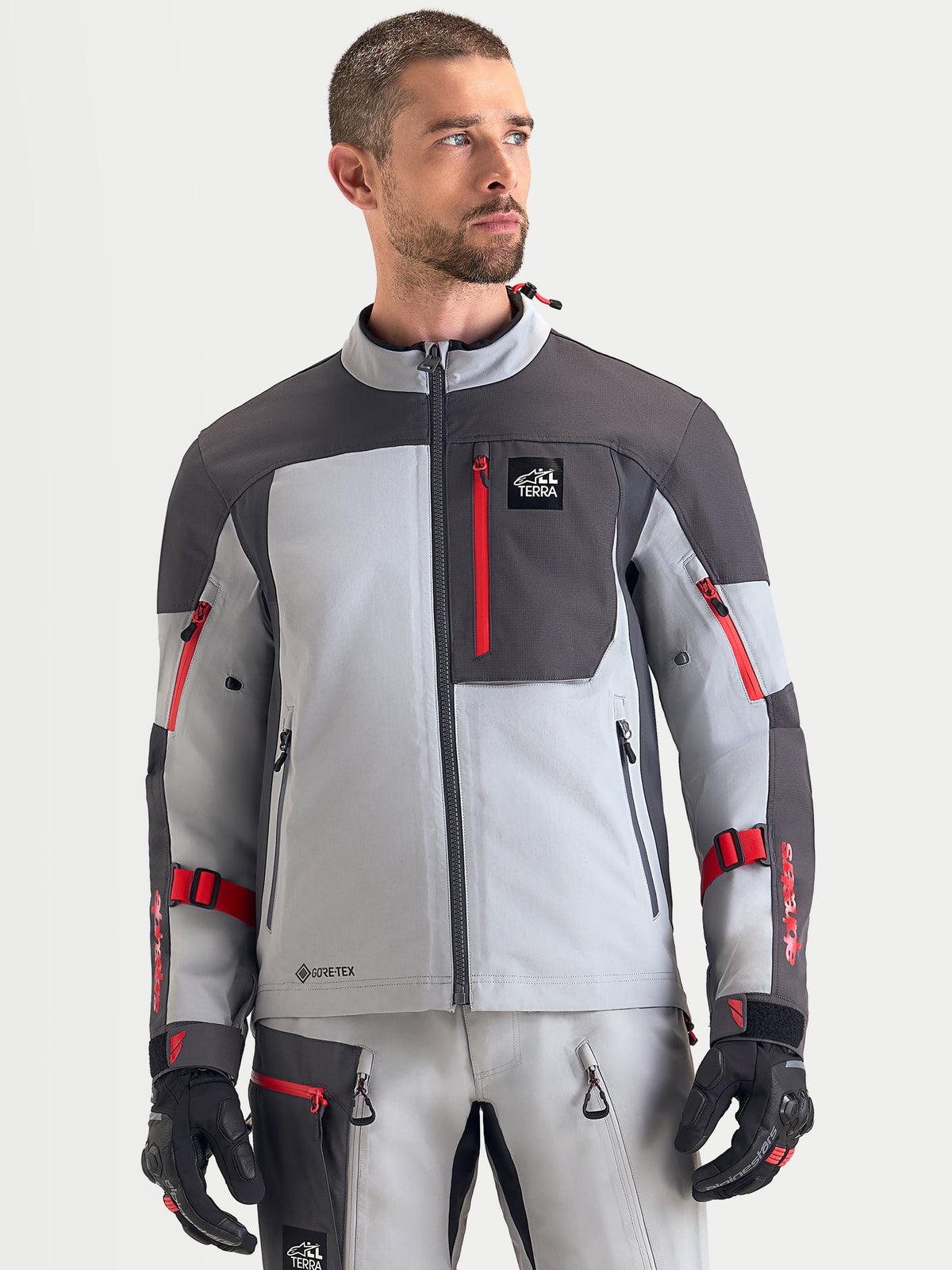 Alpinestars Arenis Gore-Tex jacka, äventyrsmotorcykeljacka för herr, mellanmörkgrå, mörkgrå och svart, framifrån på modell som visar vattentät textilkonstruktion och bröstficka med blixtlås