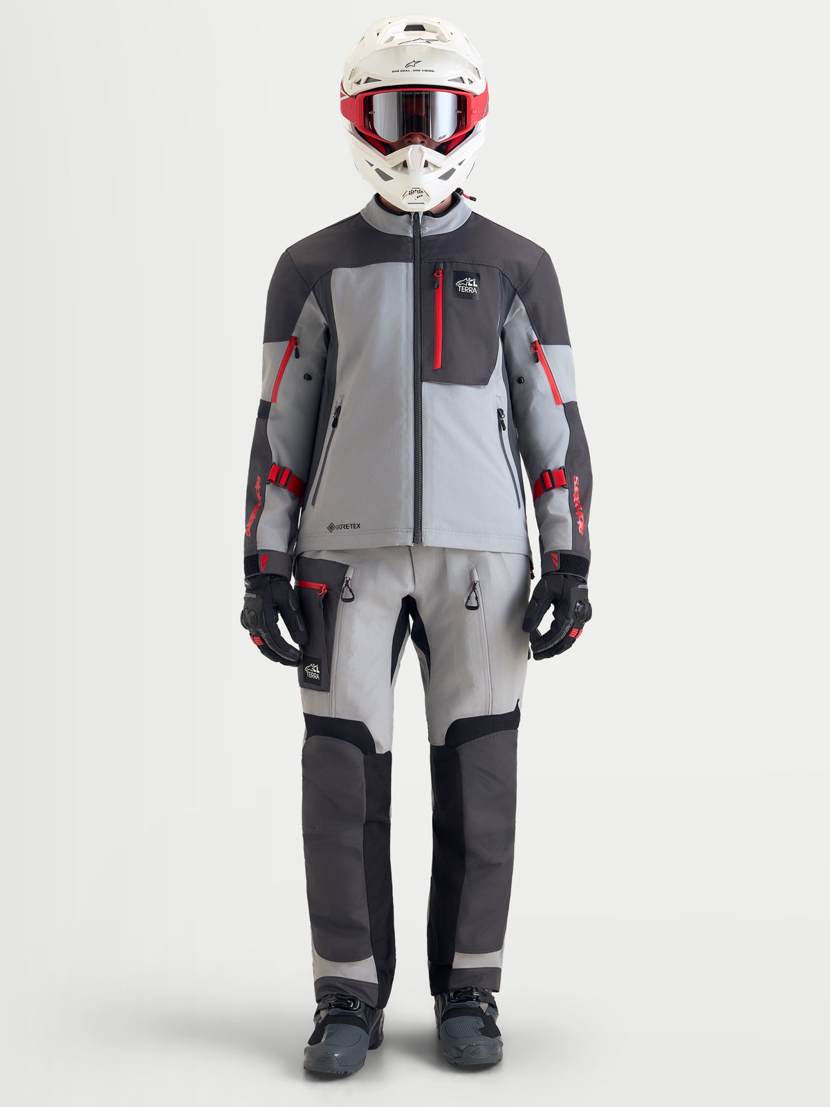 Alpinestars Arenis Gore-Tex jacka, äventyrsmotorcykeljacka för herr i mellanvitt, mörkgrå och svart, visas på modell med full äventyrsutrustning inklusive hjälm och matchande byxor