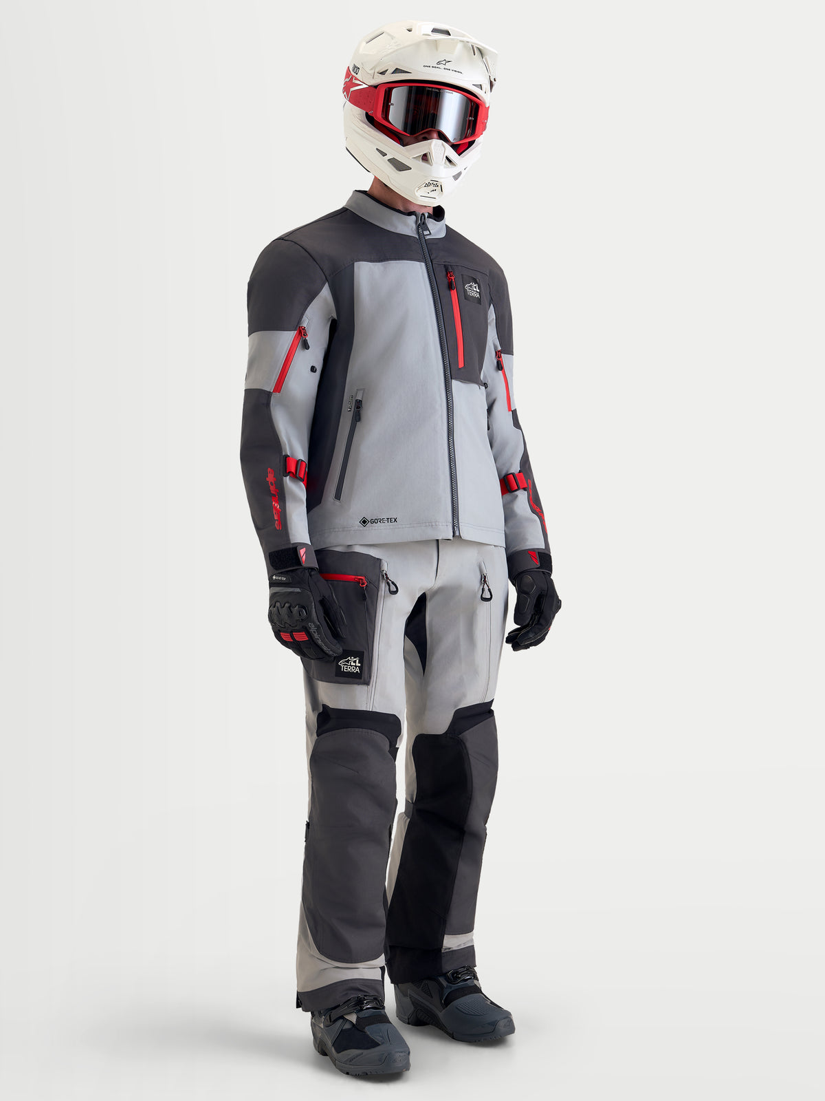 Alpinestars Arenis Gore-Tex jacka, äventyrsmotorcykeljacka för herr i mellanmörk grå, mörkgrå och svart med röda detaljer, komplett med matchande byxor, hjälm och goggles på modell