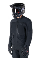 Alpinestars St-7 Prime GORE-TEX-jacka, svart motorcykeljacka, bärs av en förare med svart hjälm och goggles, stora bröstfickor i cargostil och ett laminerat vattentätt skal, premiumutrustning för adventure touring och pendling
