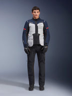 Alpinestars ST-7 2L GORE-TEX-jacka, motorcykeljacka för adventure touring, isgrå, mörkblå och svart, bärs med svarta byxor och handskar, stora utanpåliggande fickor fram, röda detaljer på ärmarna, laminerat GORE-TEX-skal för vattentät prestanda.