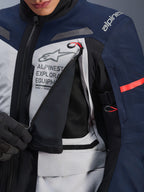 Alpinestars ST-7 2L GORE-TEX-jacka, Adventure Touring-jacka, Ice Gray, Dark Blue och svart, detaljvy av den öppnade ventilationspanelen på bröstet som visar svart mesh, med Alpinestars Exploration Equipment-logotyp och röda dragtappar