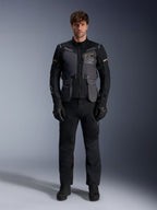 Manlig modell iklädd Alpinestars ST-7 2L GORE-TEX-jacka i färgen Deep Gray Black Dark Khaki, med 'ALPINESTARS EXPLORATION EQUIPMENT'-logotyp på bröstet, matchad med svarta mc-byxor, handskar och stövlar, studiomiljö, vy framifrån.