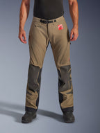 Alpinestars Nazca 3L GORE-TEX PRO-byxor i Walnut Black, äventyrstouringbyxor för herr, brunt textilmaterial med svarta Superfabric-knäförstärkningar, lårventiler med dragkedja och magnetiskt midjespänne, vy framifrån på modell med svarta stövlar, slitstark vattentät körutrustning