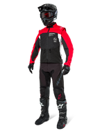 Alpinestars Pro-Dura jacka, offroad-motorcykeljacka, svart, klarröd och vit, bärs med komplett racingutrustning inklusive svart hjälm med röda goggles, svarta byxor samt svarta och vita stövlar, slitstark textiloutfit för enduro- och trailkörning