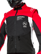 Alpinestars Pro-Dura jacka, offroad-motorcykeljacka, svart, klarröd och vit, bärs med en svart hjälm, med fickor med dragkedja och tydlig logotyp på bröstet, hållbar textilkonstruktion för enduro- och trailkörning