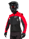 Alpinestars Pro-Dura-jacka, endurojacka för offroad, svart med klarröda och vita färgfält, bärs av en förare med svart hjälm och goggles, framfickor med dragkedja och Alpinestars-logotyp, hållbar textilkonstruktion för trailkörning