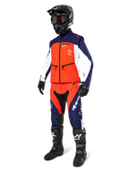 Motocross rider wearing the Alpinestars Lite-Dura Softshell Jacket in Navy Hot Orange and White, complete with matching off-road pants, black helmet with goggles, and black racing boots, coordinated enduro gear set