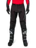 Alpinestars Pro-Dura Pants, svarta och mörkgrå endurobyxor, bärs med en röd långärmad tröja och svarta motocross-stövlar, med grå Alpinestars-logotyp och slitstark ripstop-konstruktion för terrängkörning