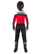 Motocrossförare iförd Alpinestars Pro-Dura-byxor i svart och Magnet, kombinerat med röd, vit och svart tröja, svart hjälm och svarta stövlar, komplett utrustning för terrängkörning, slitstark och lätt design för endurokörning