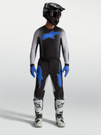 Alpinestars Supertech Hiten AFD byxor, svarta och blåa motocrossbyxor på modell med matchande tröja och vita racingstövlar.