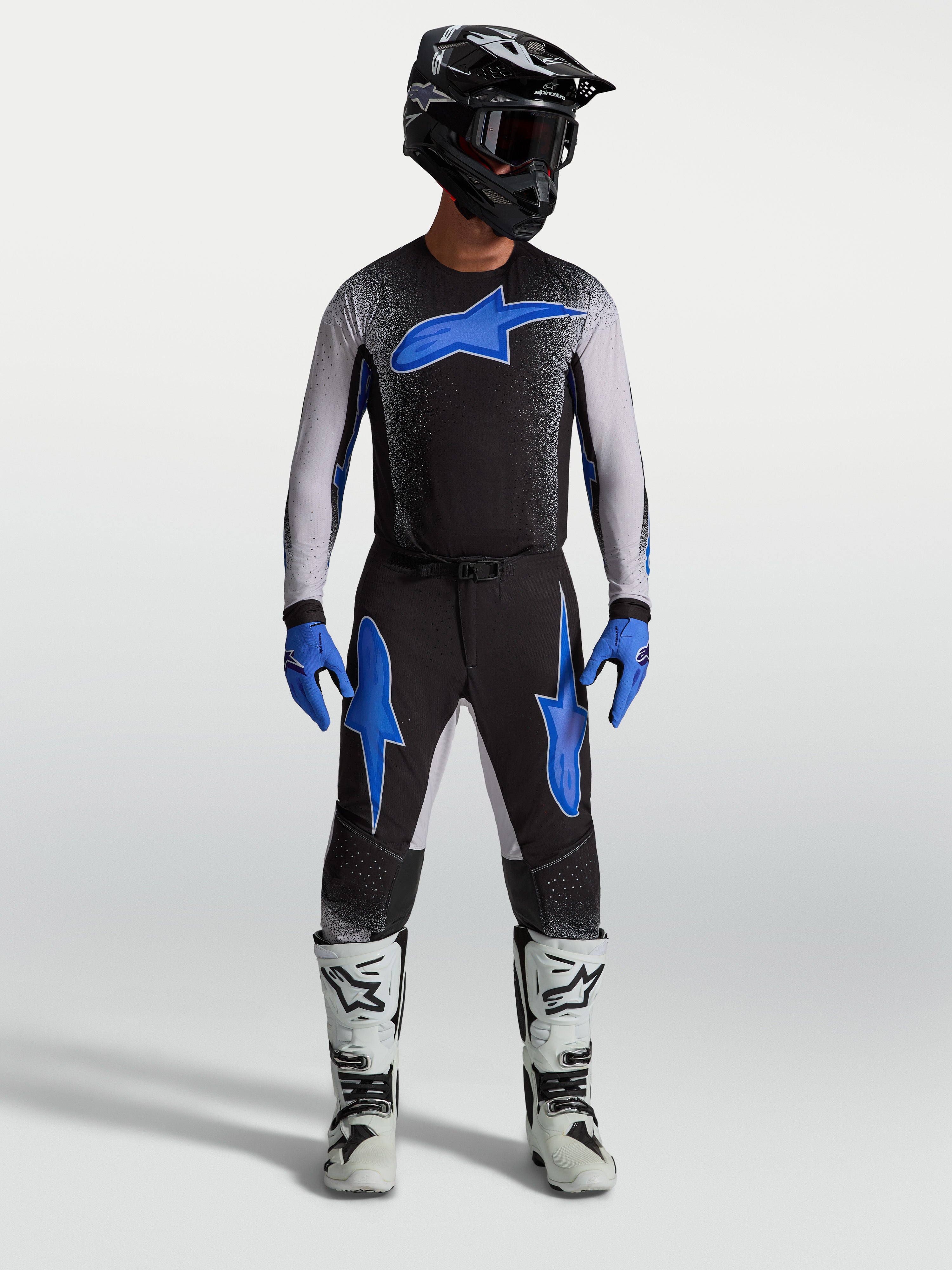 Alpinestars Supertech Hiten AFD byxor, svarta och blåa motocrossbyxor på modell med matchande tröja och vita racingstövlar.