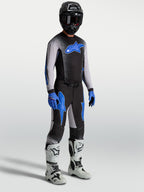 Alpinestars Supertech Hiten AFD byxor, motocrossbyxor på modell med matchande tröja och vita stövlar, svarta och blå.