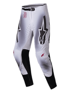 Alpinestars 2025 Supertech Maker Pants, Motocross Pants, Silver and Black, featuring large black Astars logos on the thighs, red technical branding on the hip, black leather inner knee panels, and perforated ventilation zones.