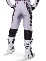 Alpinestars 2025 Supertech Maker-byxor, motocrossbyxor, silver och svarta, vy bakifrån som visar stora svarta logotyper på låren och ventilerande mesh-zoner bakom knäna, bärs med vita Alpinestars-stövlar