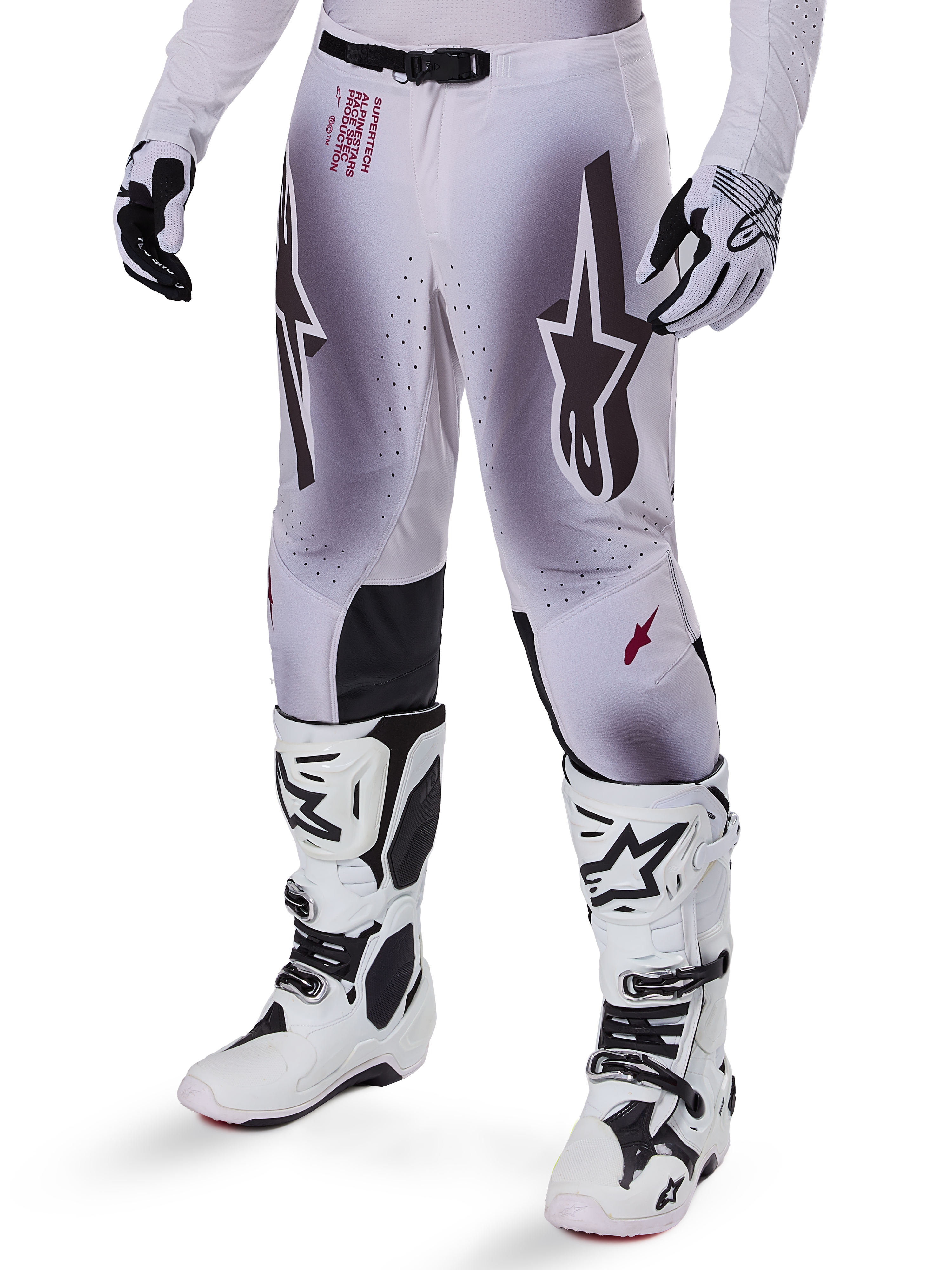 Alpinestars 2025 Supertech Maker-byxor, motocrossbyxor, silver och svarta, med stora stjärnlogotyper och röd text, visas med matchande vita stövlar och handskar