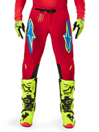 Alpinestars 2025 Supertech Maker Pants, Motocross Pants, Bright Red and Yellow Fluo, featuring blue Astars logos on the thighs, ventilated perforations, and black inner knee panels, worn with matching yellow fluo boots and gloves