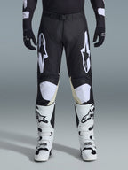 Alpinestars 2026 Racer Air Riway-byxor, motocrossbyxor, svarta och vita, med framträdande vita Alpinestars-logotyper på låren och knäpanelerna, kombinerat med vita och svarta motocross-stövlar och svarta handskar, atletisk race-fit-design för terrängkörning