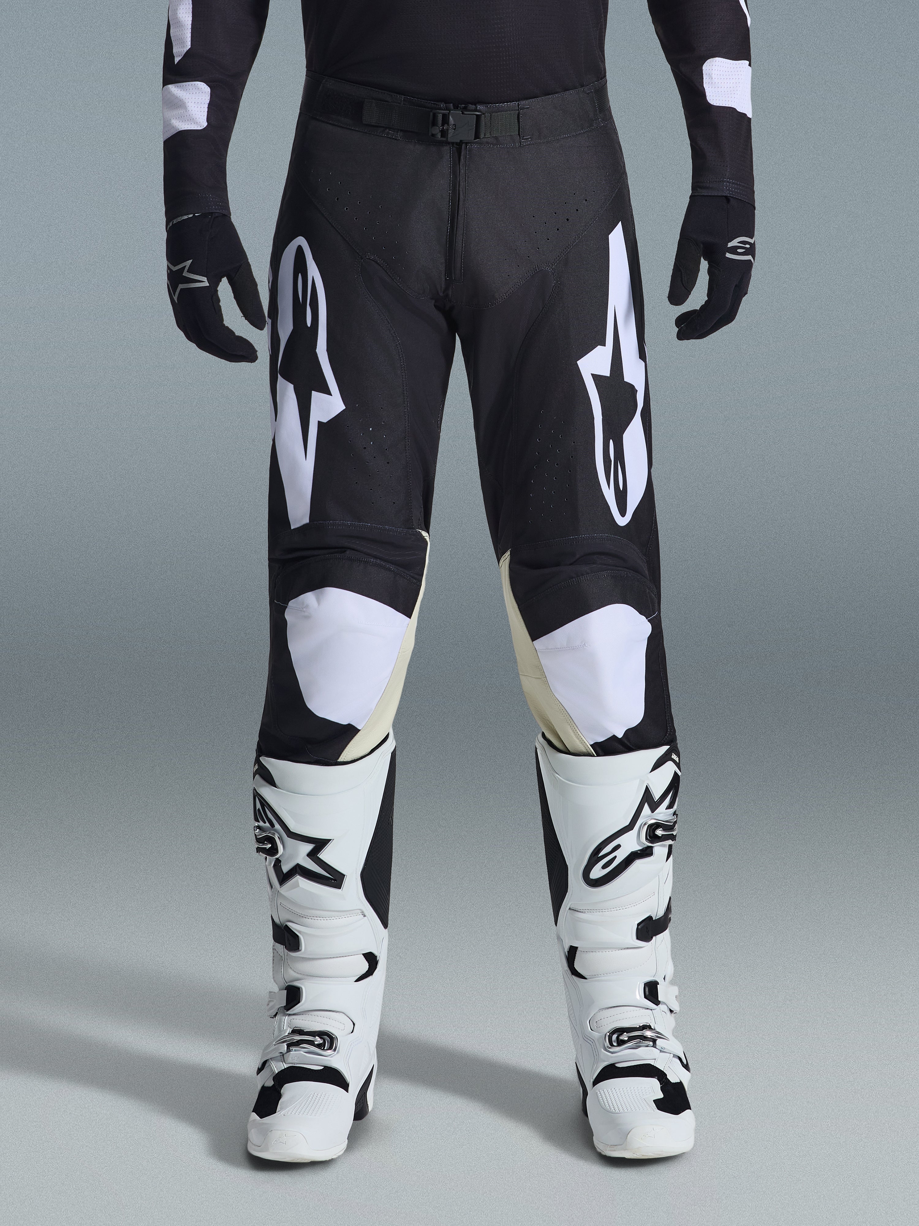 Alpinestars 2026 Racer Air Riway-byxor, motocrossbyxor, svarta och vita, med framträdande vita Alpinestars-logotyper på låren och knäpanelerna, kombinerat med vita och svarta motocross-stövlar och svarta handskar, atletisk race-fit-design för terrängkörning